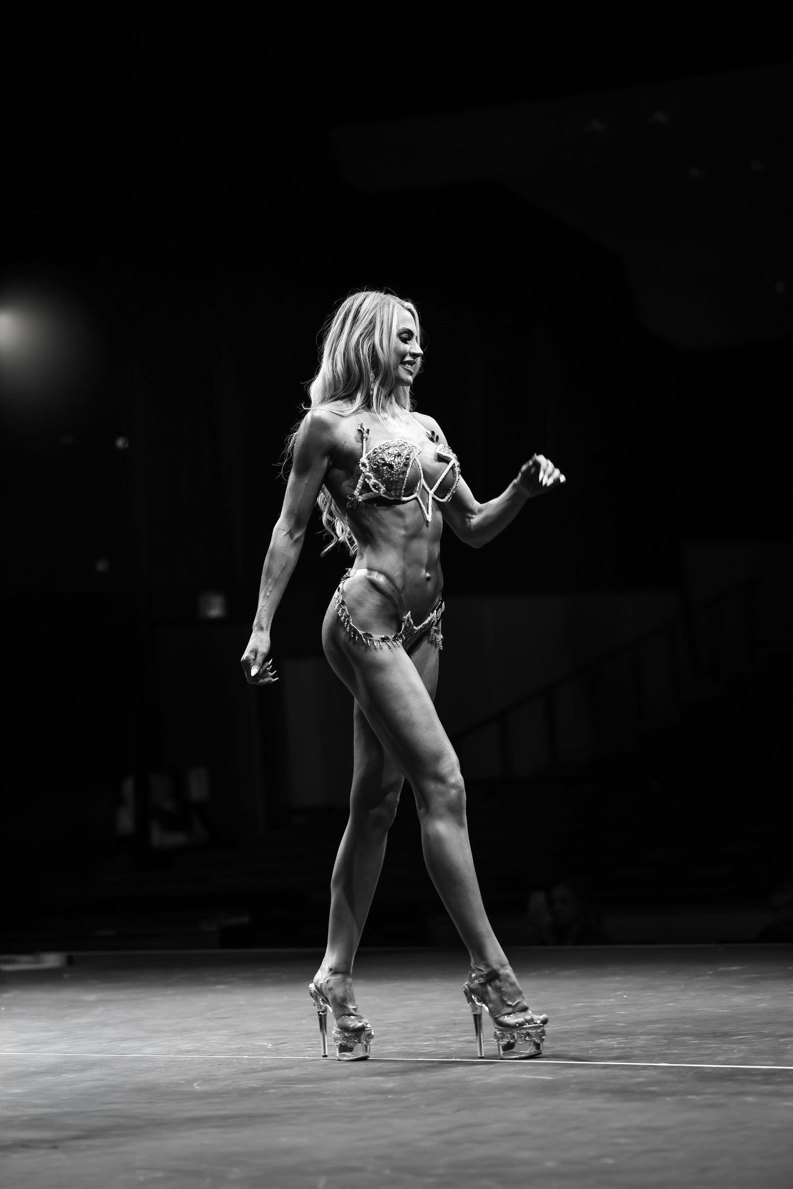 A competitor walks the FMG USA 2026 stage in Dallas under a single spotlight