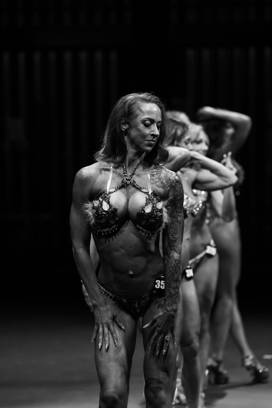 A competitor holds her pose on stage as the line-up stands behind her